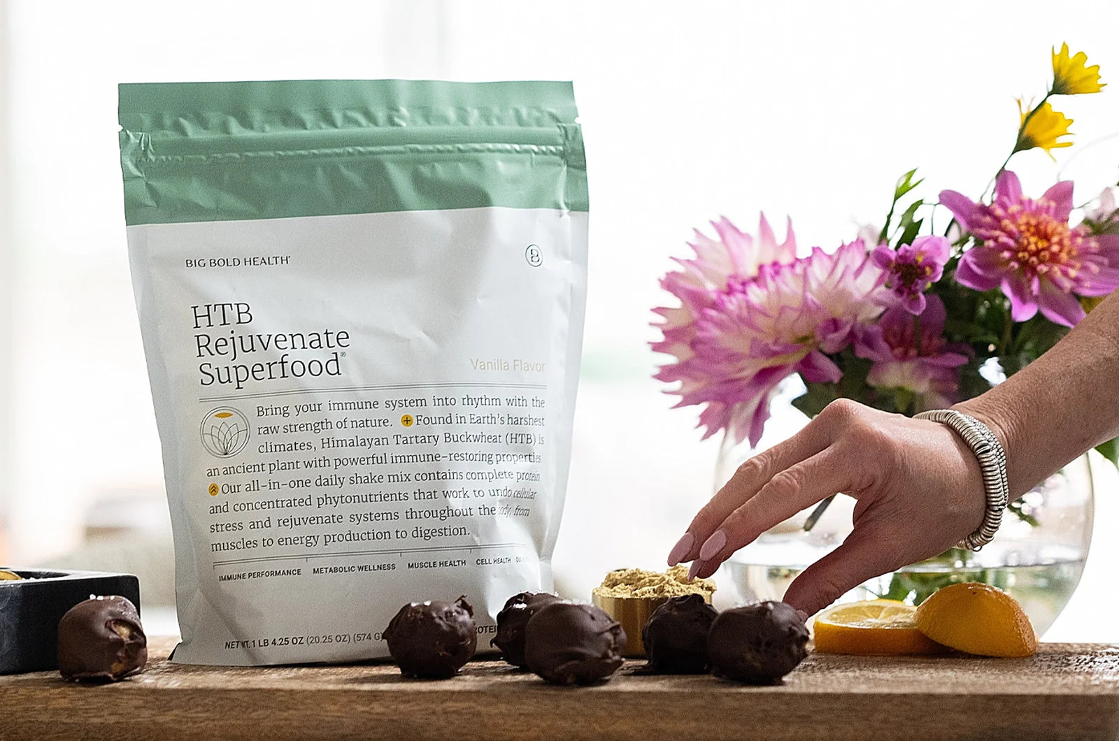 A woman's hand reaching for a protein ball beside a bag of superfood