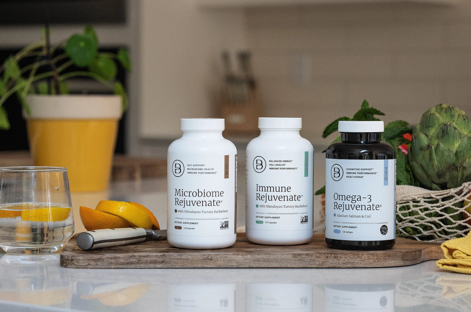 Three bottles of supplements sitting on a cutting board in a kitchen food prep setting