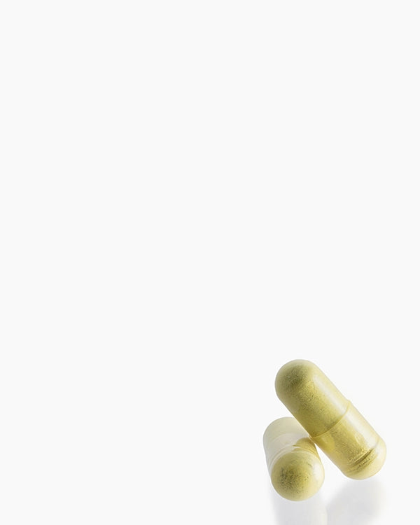 Two pale yellow-green capsules lying on a clean white background.