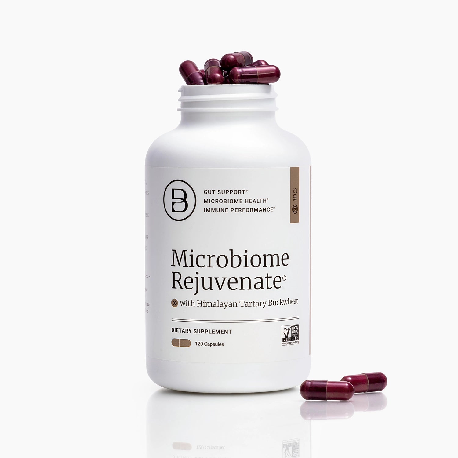 A white bottle of Microbiome Rejuvenate dietary supplement with capsules spilling out from the top and two capsules lying on the surface in front, set against a clean white background.