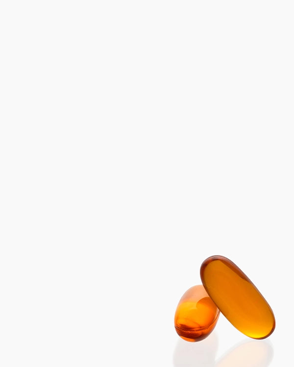 Two translucent amber-orange softgel capsules standing upright on a clean white background.